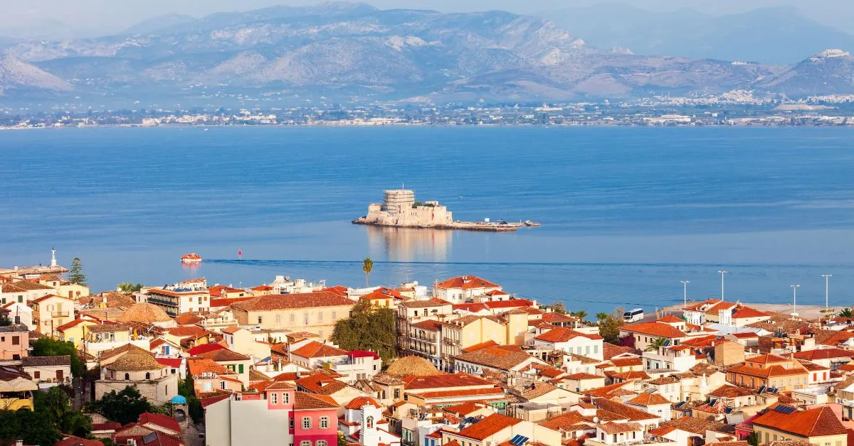 realistic photo of a city next to the sea with a lot of houses with red tile roofs and a castle on a tiny island in the background