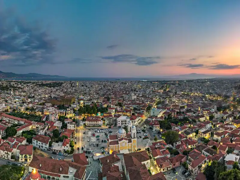 realistic photo of a city featuring a lot of houses with red tile roofs and main roads and the main square