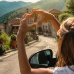 close up photo of a woman reaching out of a car window and making a heart shape with her hands in village road