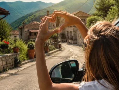 close up photo of a woman reaching out of a car window and making a heart shape with her hands in village road